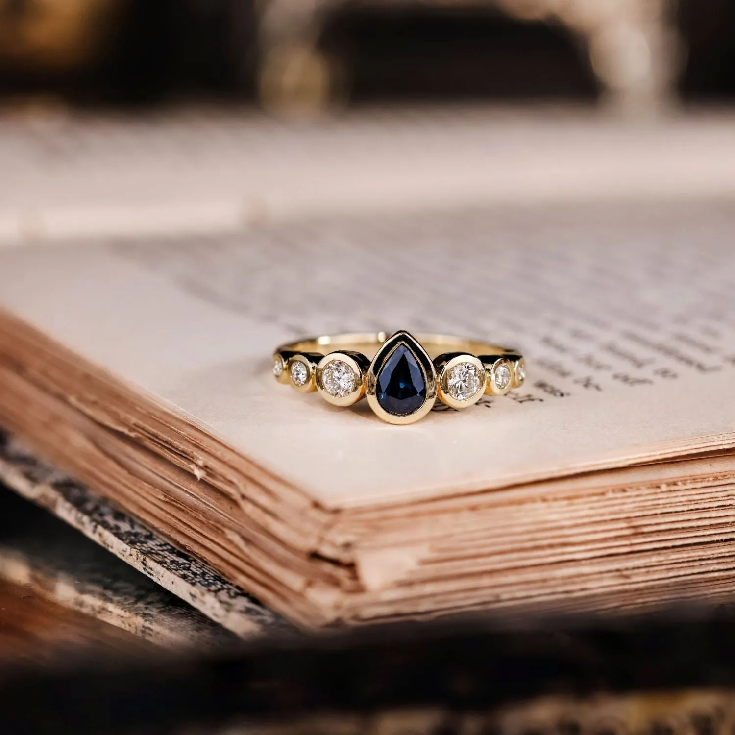 The Lyra - Bezel Set Pear Cut Blue Sapphire Engagement Ring with Diamond Accents