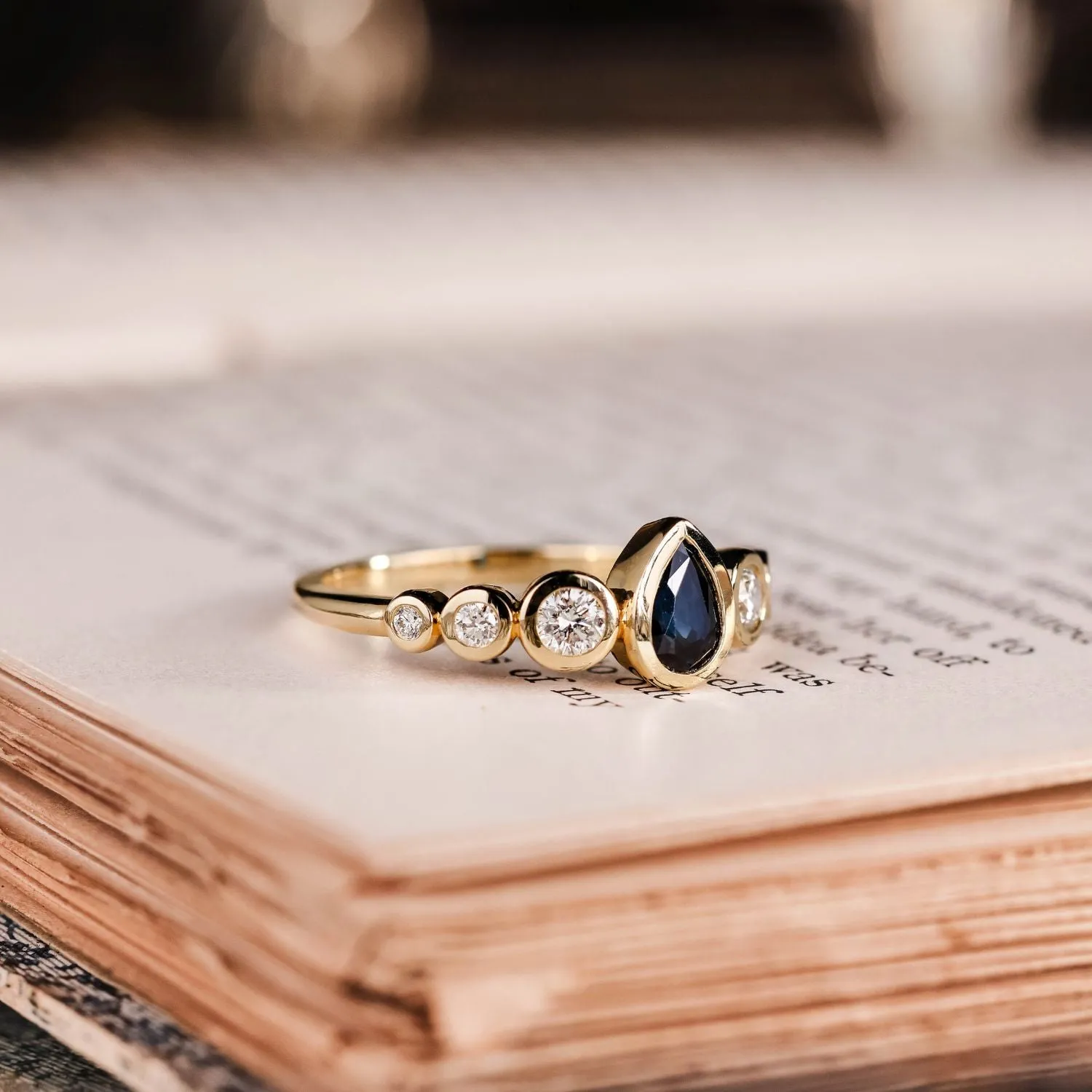 The Lyra - Bezel Set Pear Cut Blue Sapphire Engagement Ring with Diamond Accents