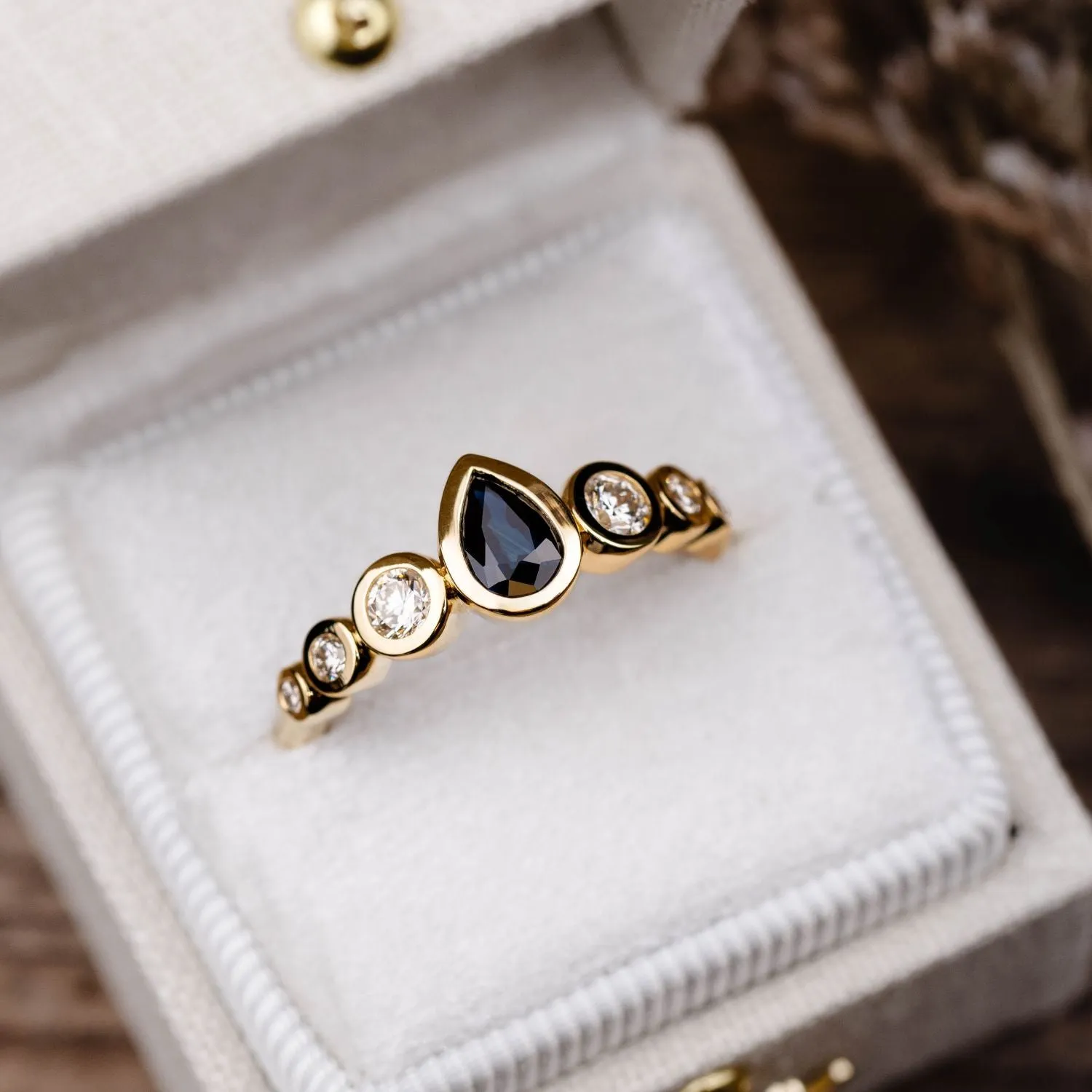 The Lyra - Bezel Set Pear Cut Blue Sapphire Engagement Ring with Diamond Accents